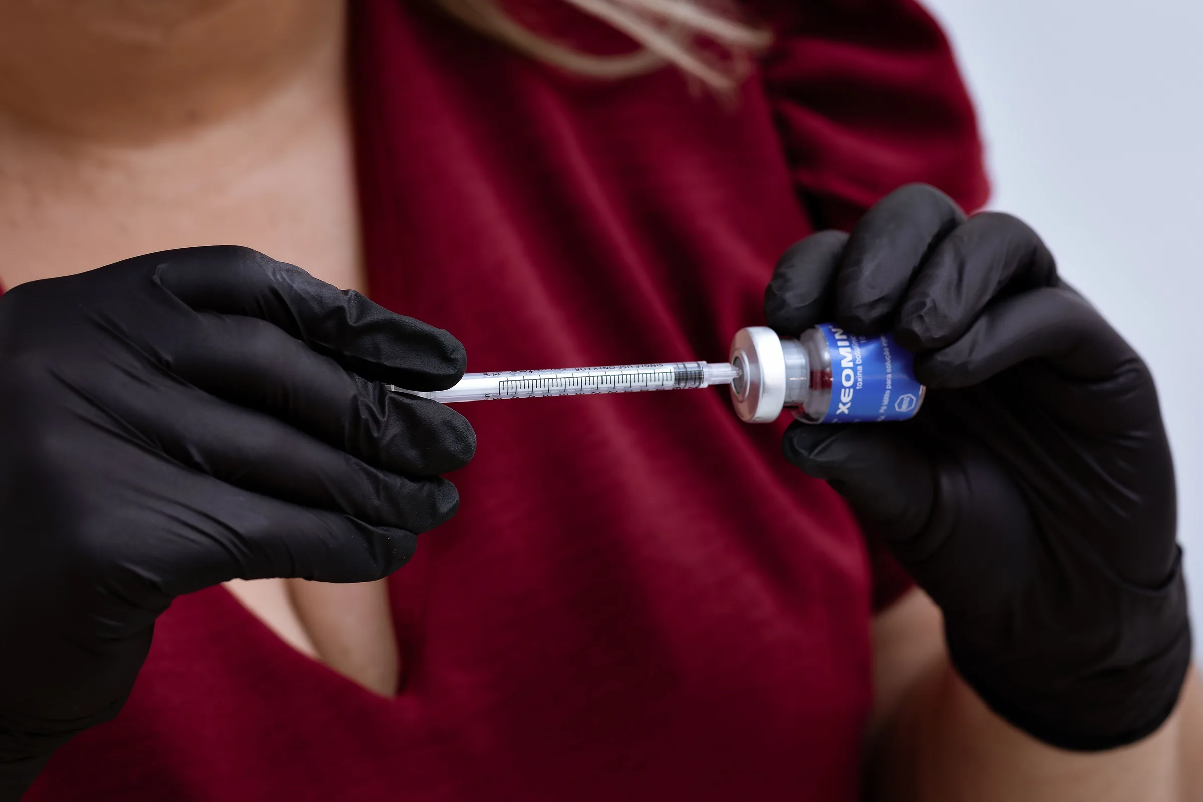 Gloved hands holding a syringe with blue medication vial for weight loss injection.